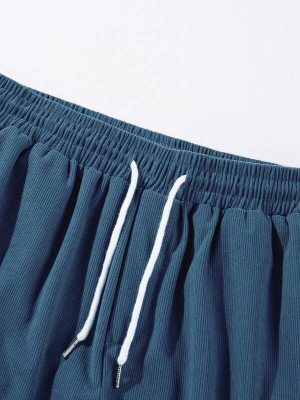 Close-up of teal corduroy waistband with white drawstring cords and ribbed texture