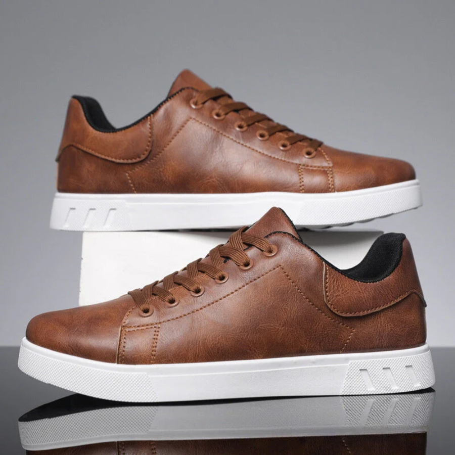 Pair of brown leather lace-up sneakers stacked on white plinth