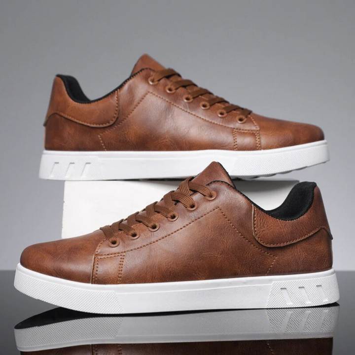 Pair of brown leather lace-up sneakers stacked on white plinth