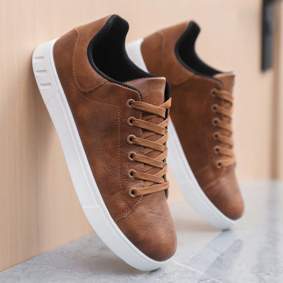 Brown leather lace-up sneakers with white soles resting on marble surface