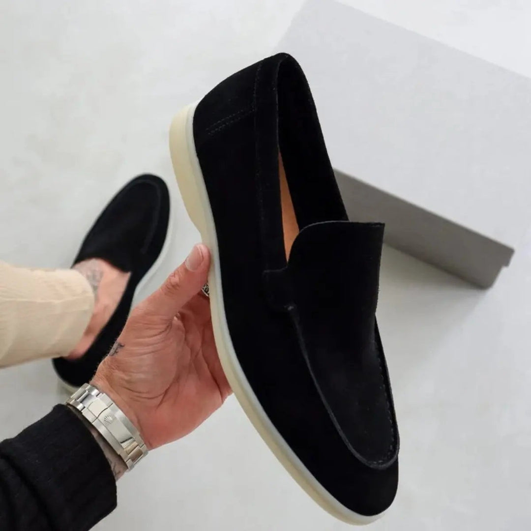 Hand holding black suede loafer showing white flatform sole detail