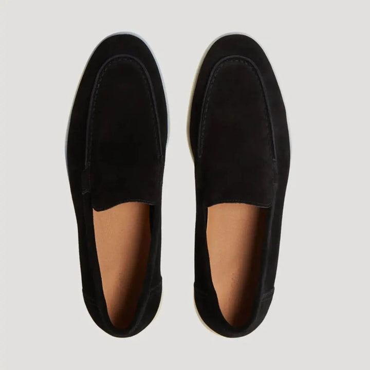 Overhead view of black suede loafers with tan leather insoles