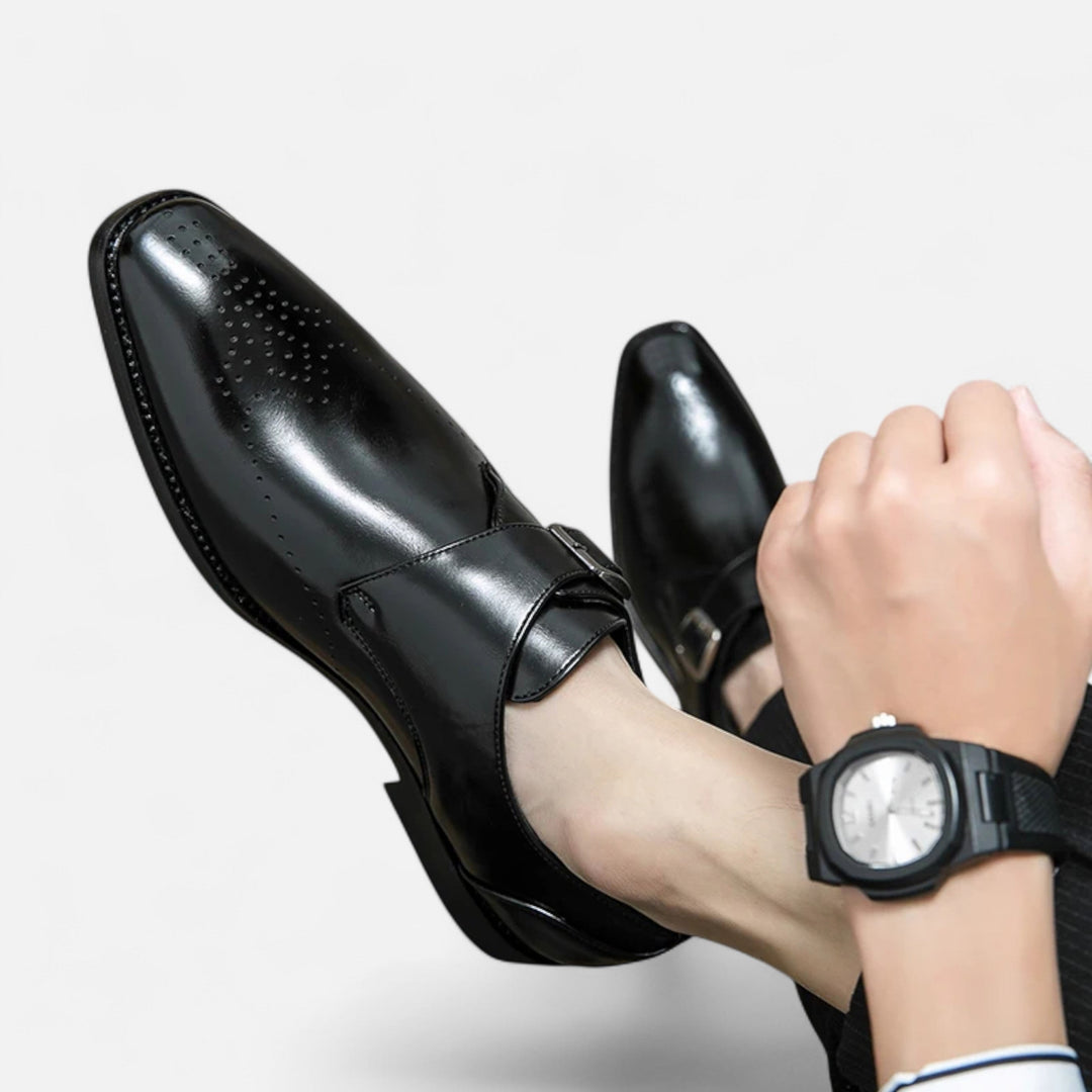 Close-up of black leather monk strap shoes with silver buckle and pointed toe