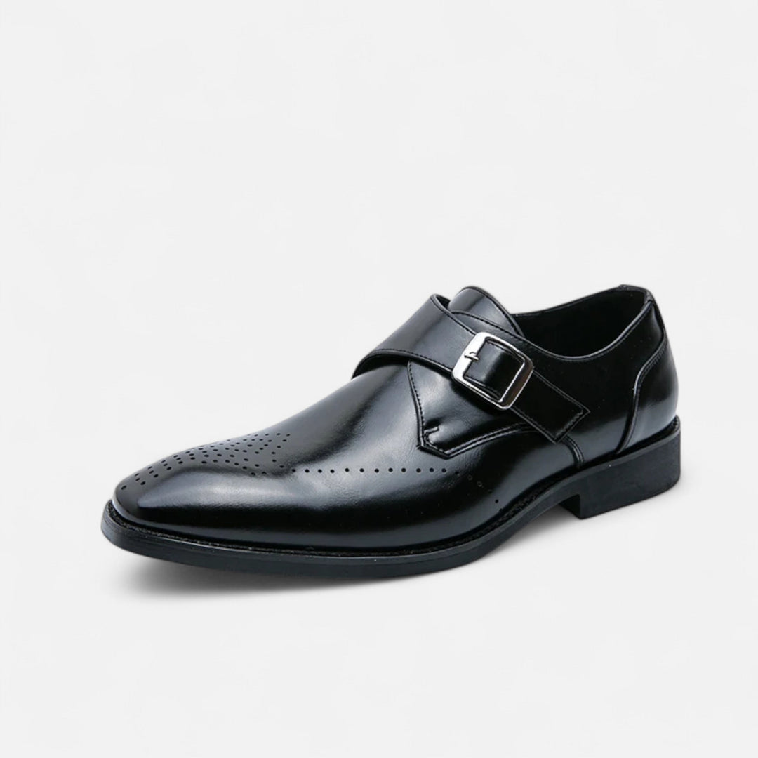 Black leather brogue monk strap shoe shown at an angle against a plain background