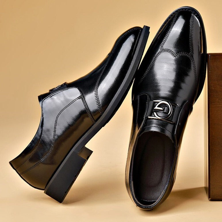 Pair of black leather slip-on dress shoes with polished finish beside a box