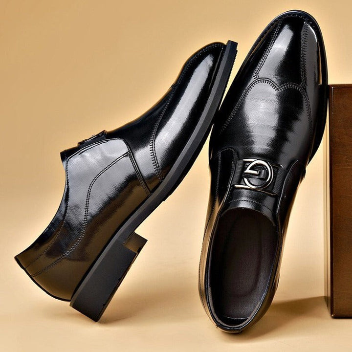Pair of black leather slip-on dress shoes with polished finish beside a box