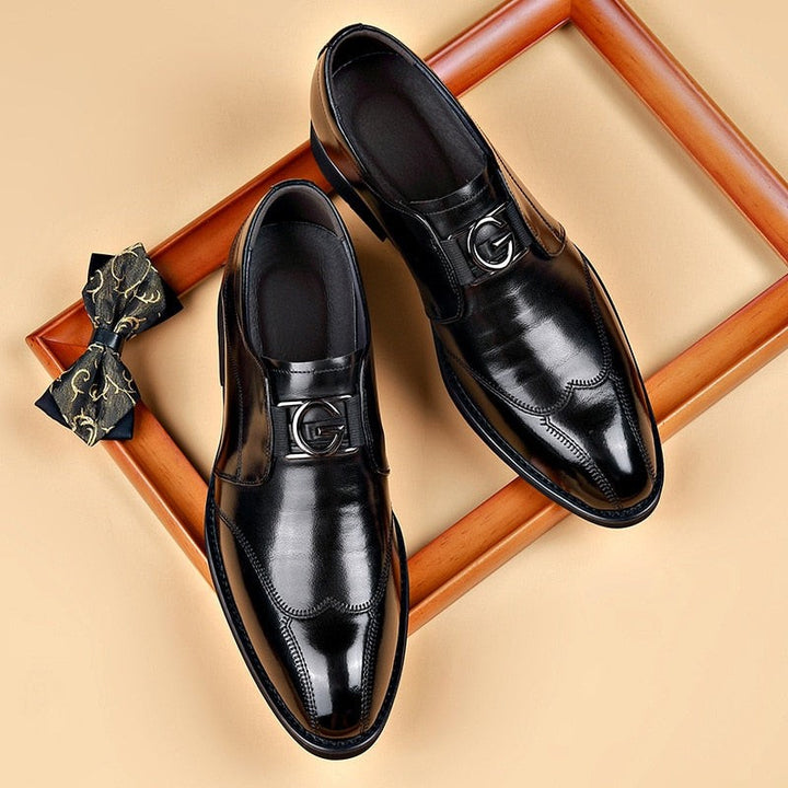 Black leather loafers with silver buckle detail, paired with a patterned bow tie