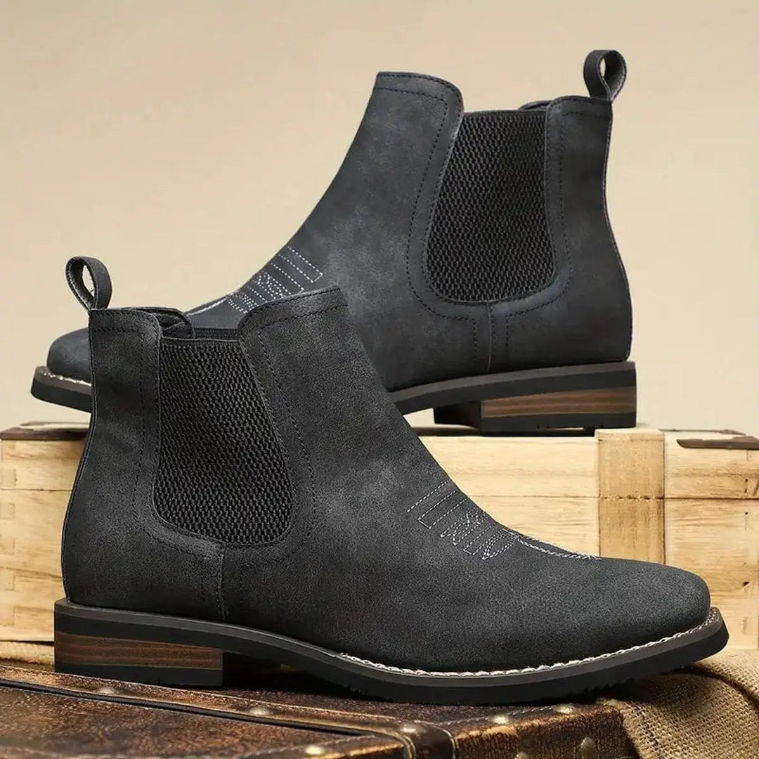 Black Chelsea boots with woven elastic gussets displayed on trunk
