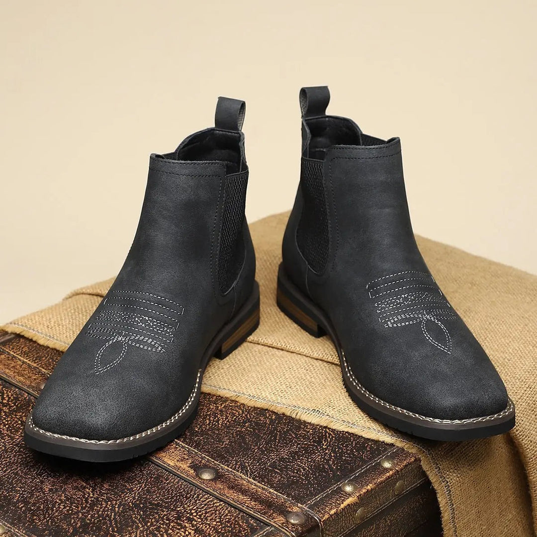 Pair of black ankle boots with western stitch design on toe