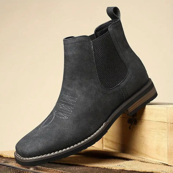 Black suede-style Chelsea boot balanced on wooden crate edge