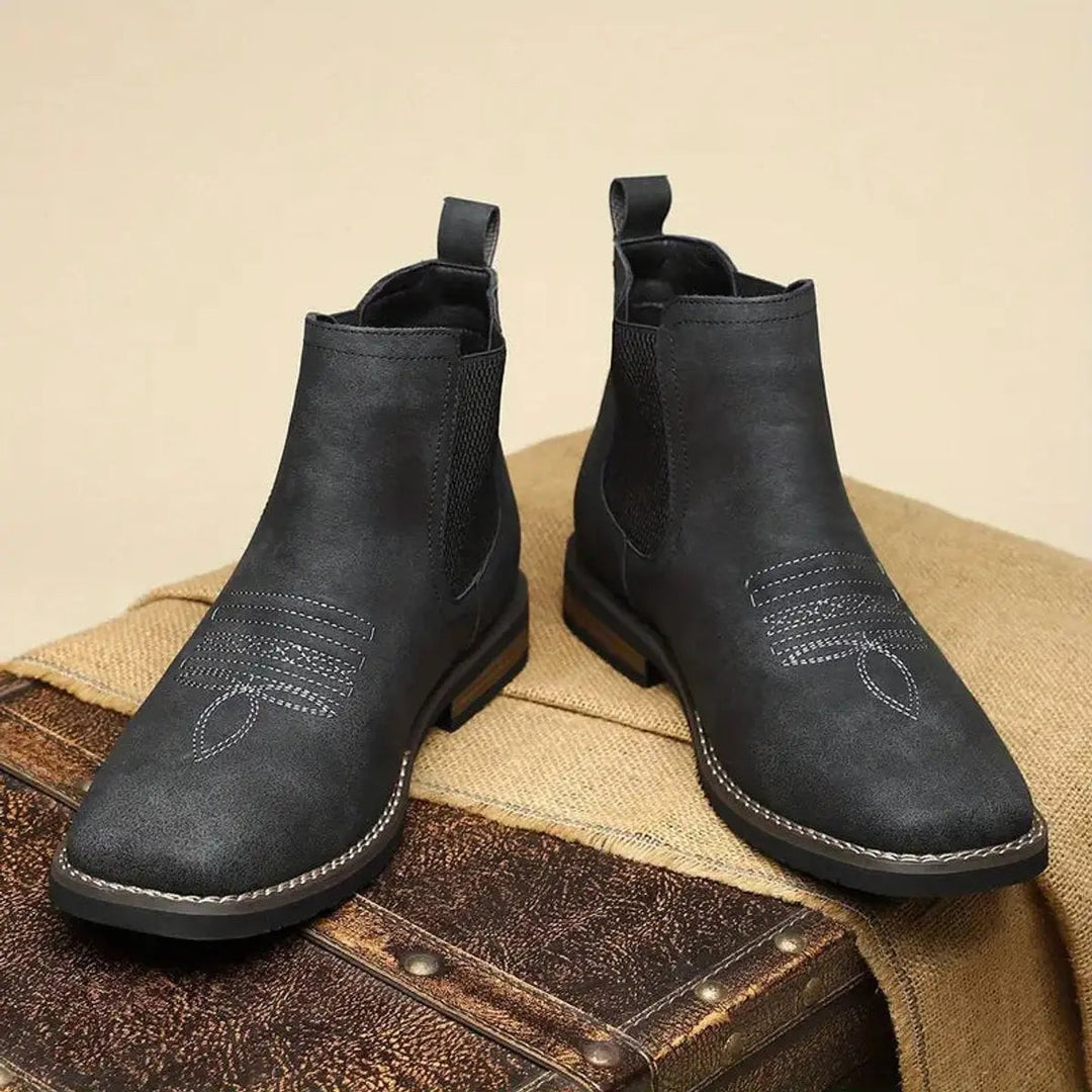 Black Chelsea boots viewed from the front with stitched toe pattern