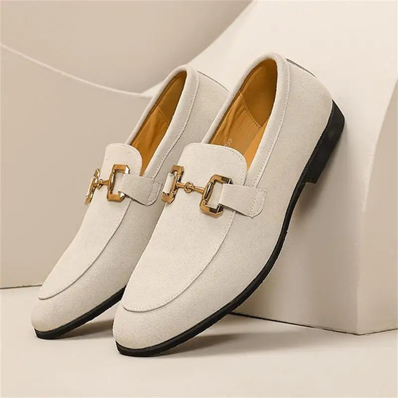 Cream suede loafers featuring gold snaffle bar, presented on a plain backdrop