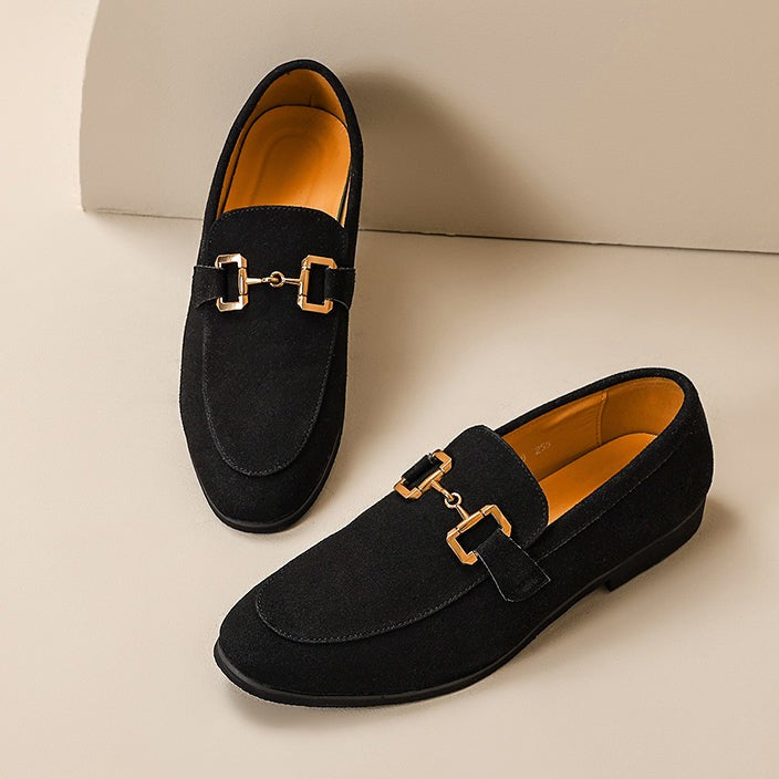Black suede loafers with gold metal detail, shown in a studio pair