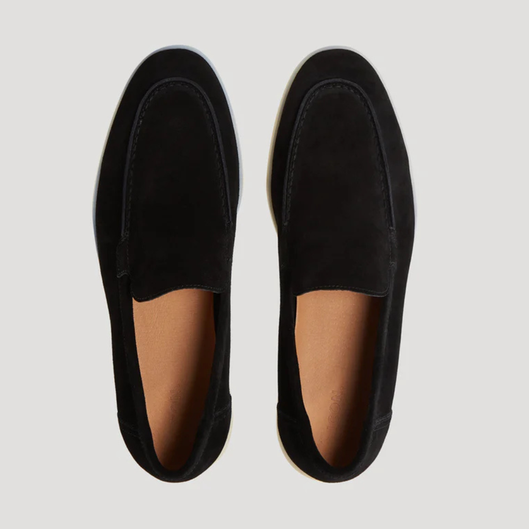 Top-down view of black suede loafers with contrast white soles
