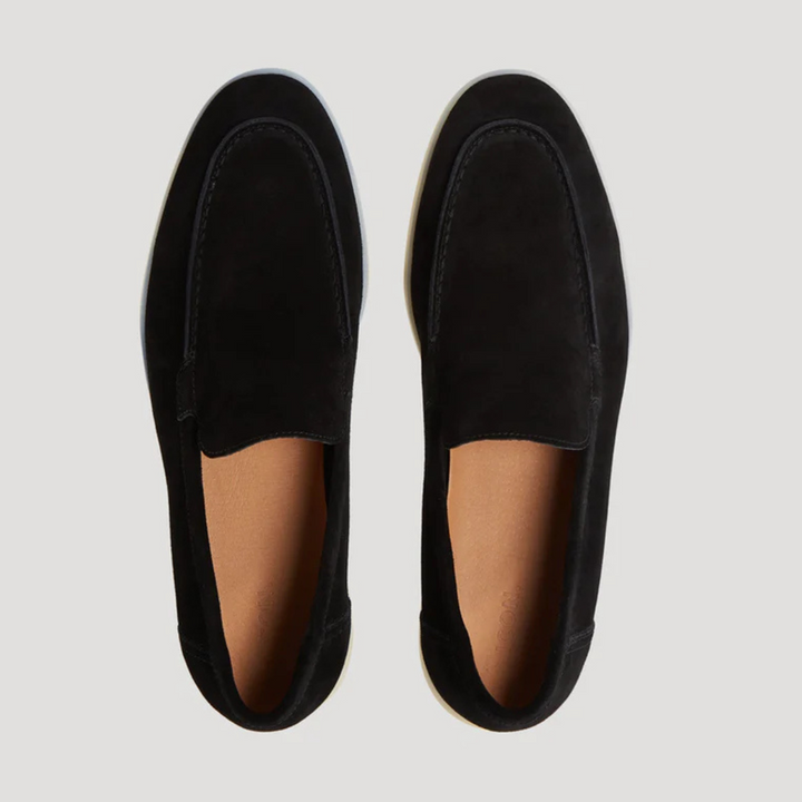 Top-down view of black suede loafers with contrast white soles