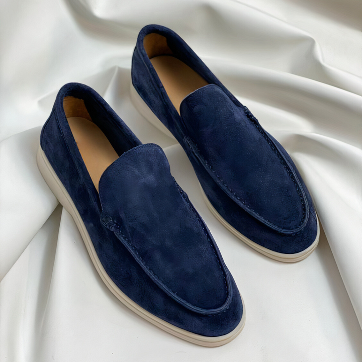 Navy suede loafers with white soles styled on white fabric
