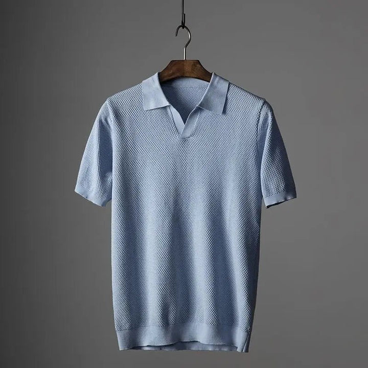 Pale blue textured knit polo shirt with short sleeves on wooden hanger