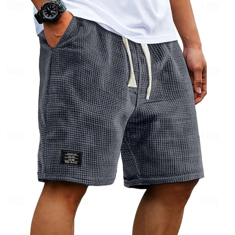Charcoal grey waffle-textured men's shorts with drawstring waist and logo patch