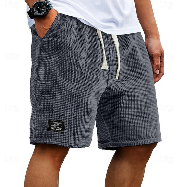 Charcoal grey waffle-textured men's shorts with drawstring waist and logo patch