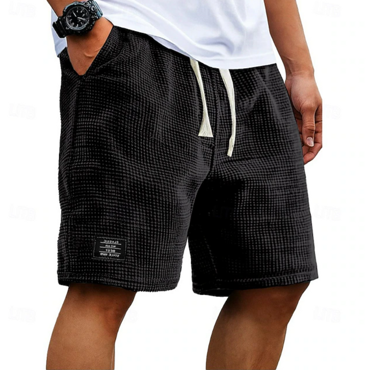 Black textured waffle shorts with cream drawstring and branded patch detail