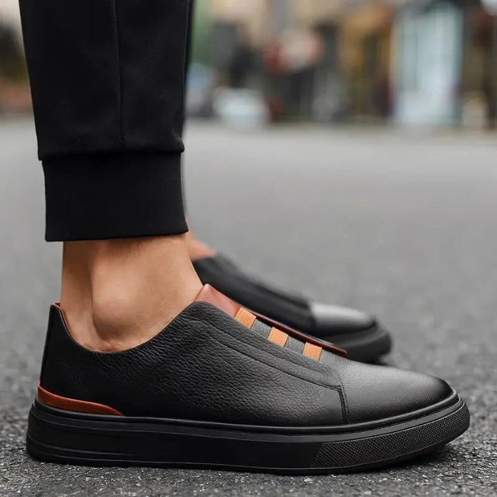 Black leather trainers with tan heel trim worn with tailored trousers