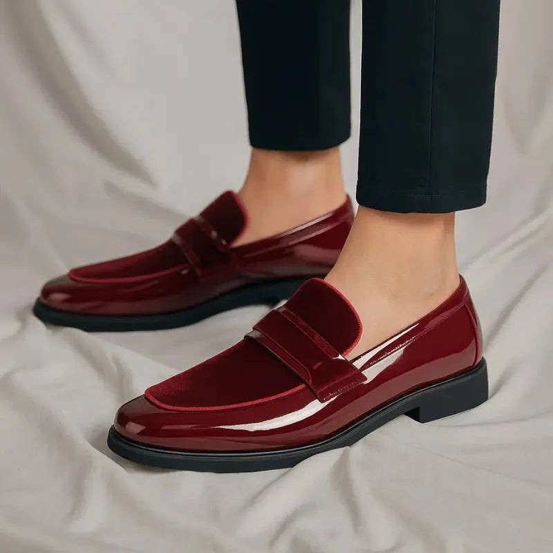Close-up of burgundy patent loafers worn with dark trousers, suede accent visible