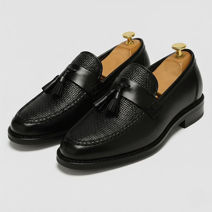 Black leather tassel loafers with woven textured toe and saddle strap detail