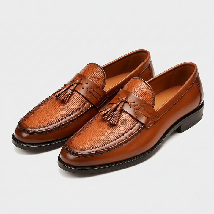 Tan leather tassel loafers featuring textured toe panel and stacked heel