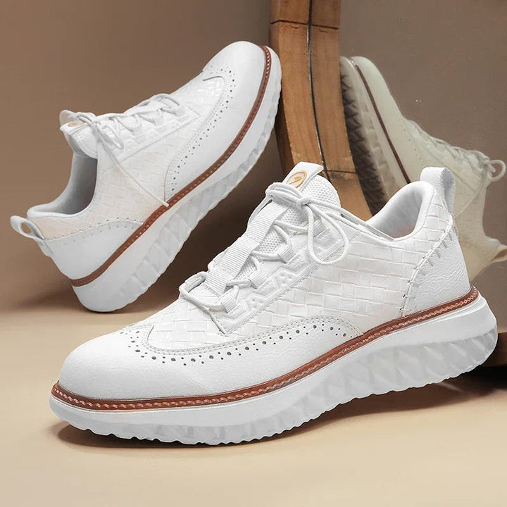 Pair of white woven leather trainers with tan-trimmed soles and reflective backdrop
