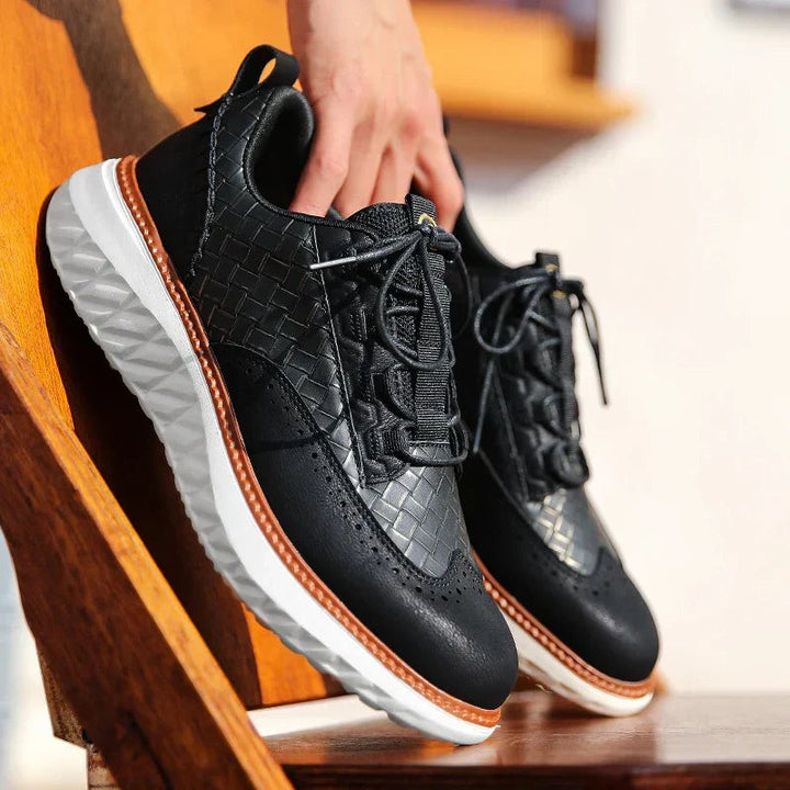 Black woven leather platform trainers held above a wooden bench, laces loose