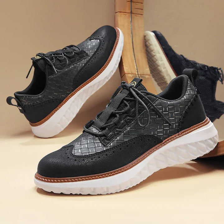 Pair of black woven leather brogue trainers with white chunky soles on display