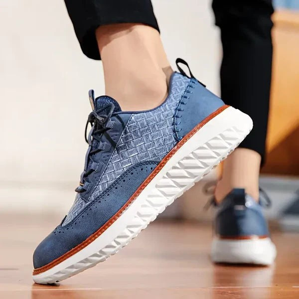 Navy leather brogue trainer in motion, highlighting textured woven side panel