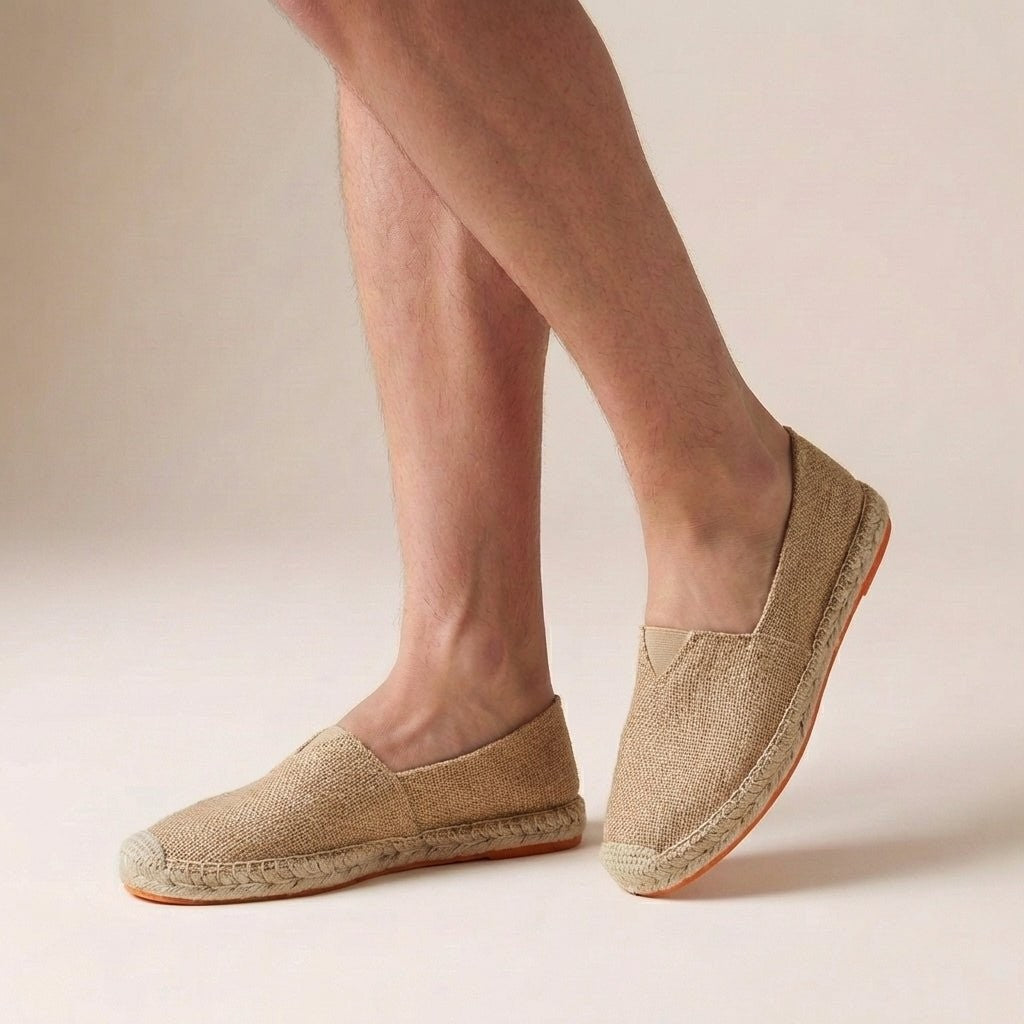 Sandy tan woven espadrilles with orange-tinted jute sole, worn on feet