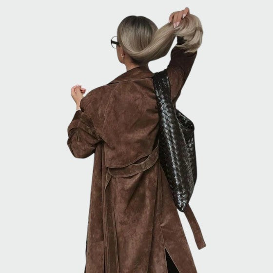 Rear view of brown suede trench coat worn with a woven backpack