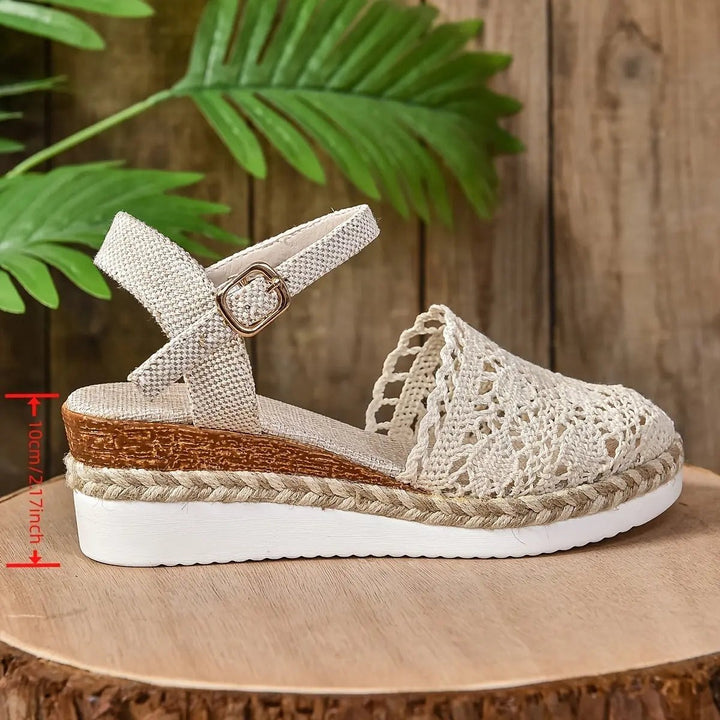 Cream woven espadrille sandal with buckle strap measured against wooden backdrop