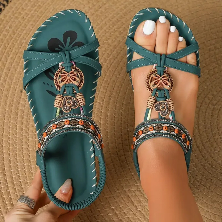 Teal flat sandals with beaded T-strap and butterfly charm detail