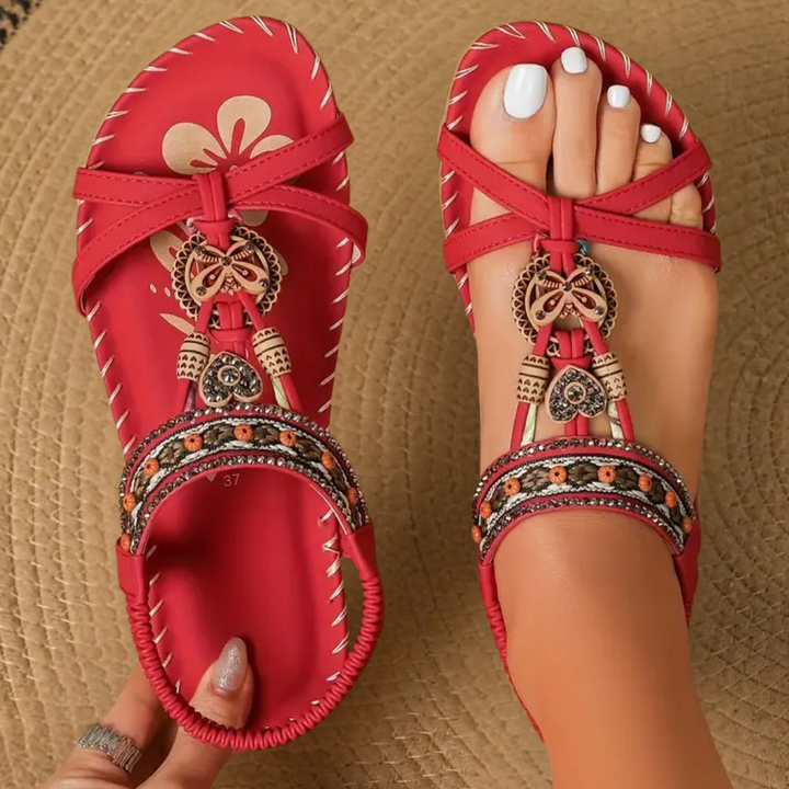 Red T-strap flat sandals featuring beaded trim and butterfly charm