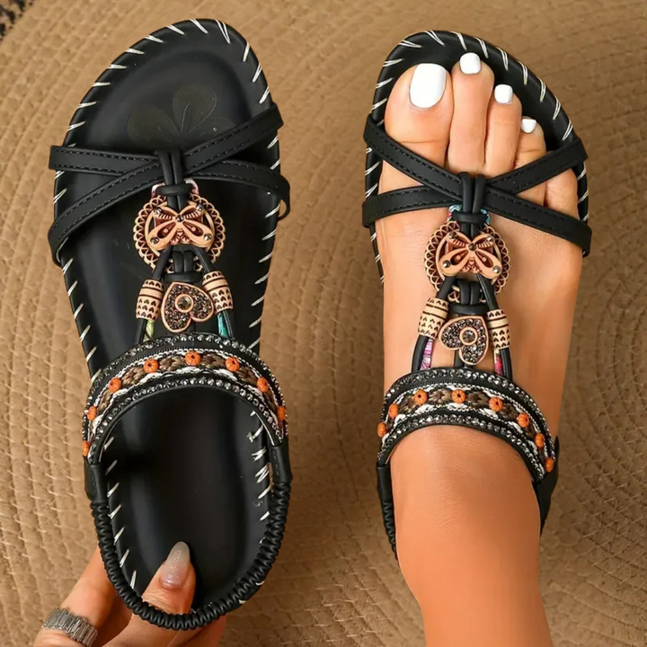 Black flat sandals with woven beaded strap and butterfly detail