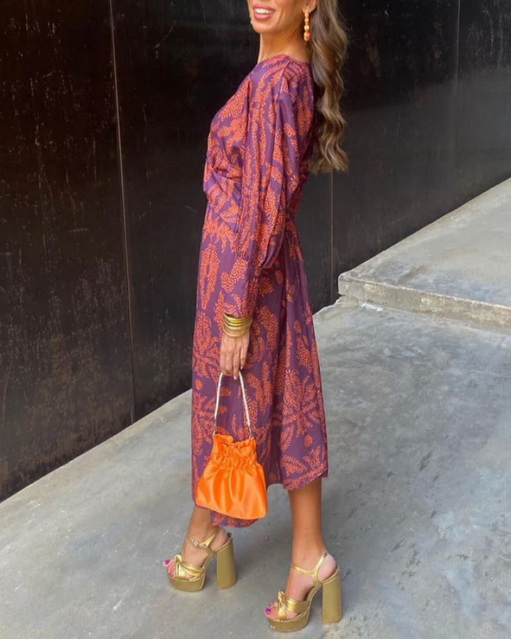 Side view of purple maxi dress with orange print, batwing sleeves and gold heels