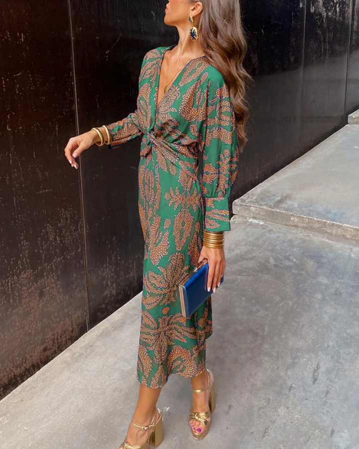 Green maxi dress with plunging V-neck styled with gold cuffs and blue clutch bag