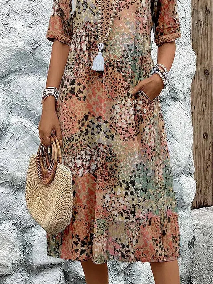 Detail view of patchwork print midi dress showing pocket and straw handbag
