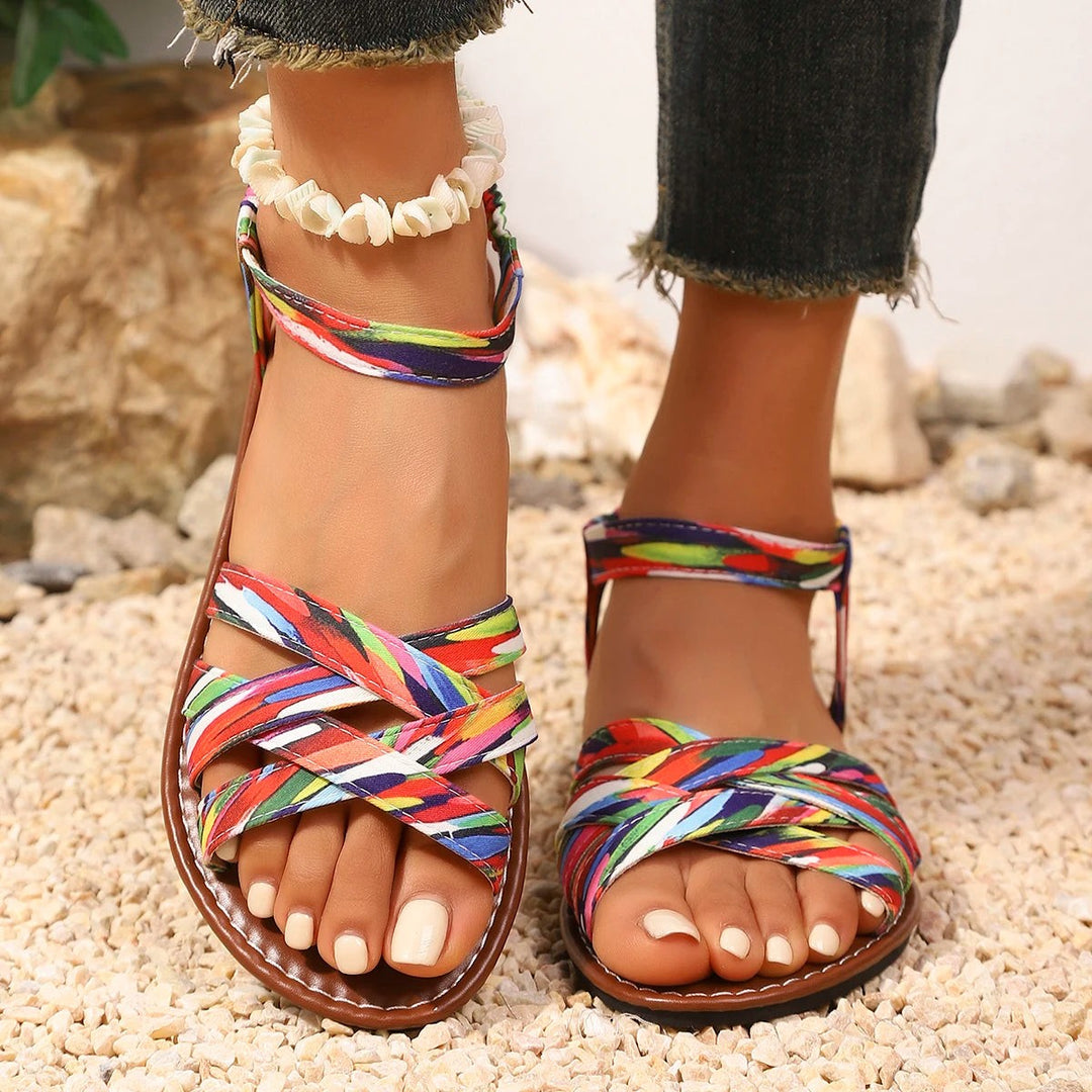 Close-up view of multicoloured flat sandals with woven elasticated ankle strap