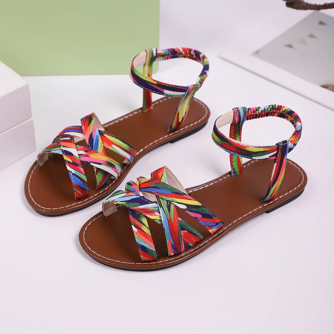 Multicoloured flat sandals shown from side with woven ankle strap design