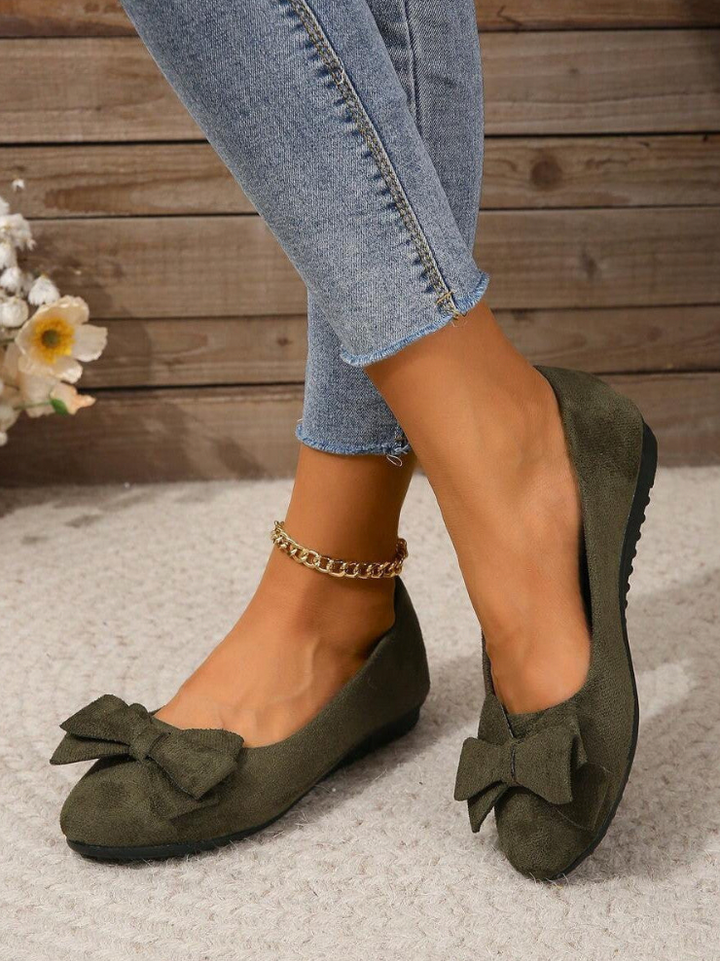 Olive green flat shoes with bow detail worn with cropped jeans