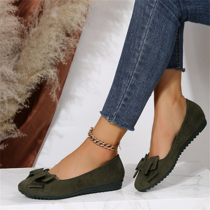 Khaki suede-effect flats with bow accent styled with skinny jeans