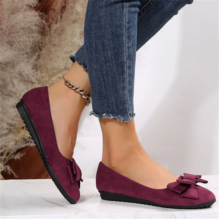 Wine red bow-trim flat shoes worn with cropped denim jeans