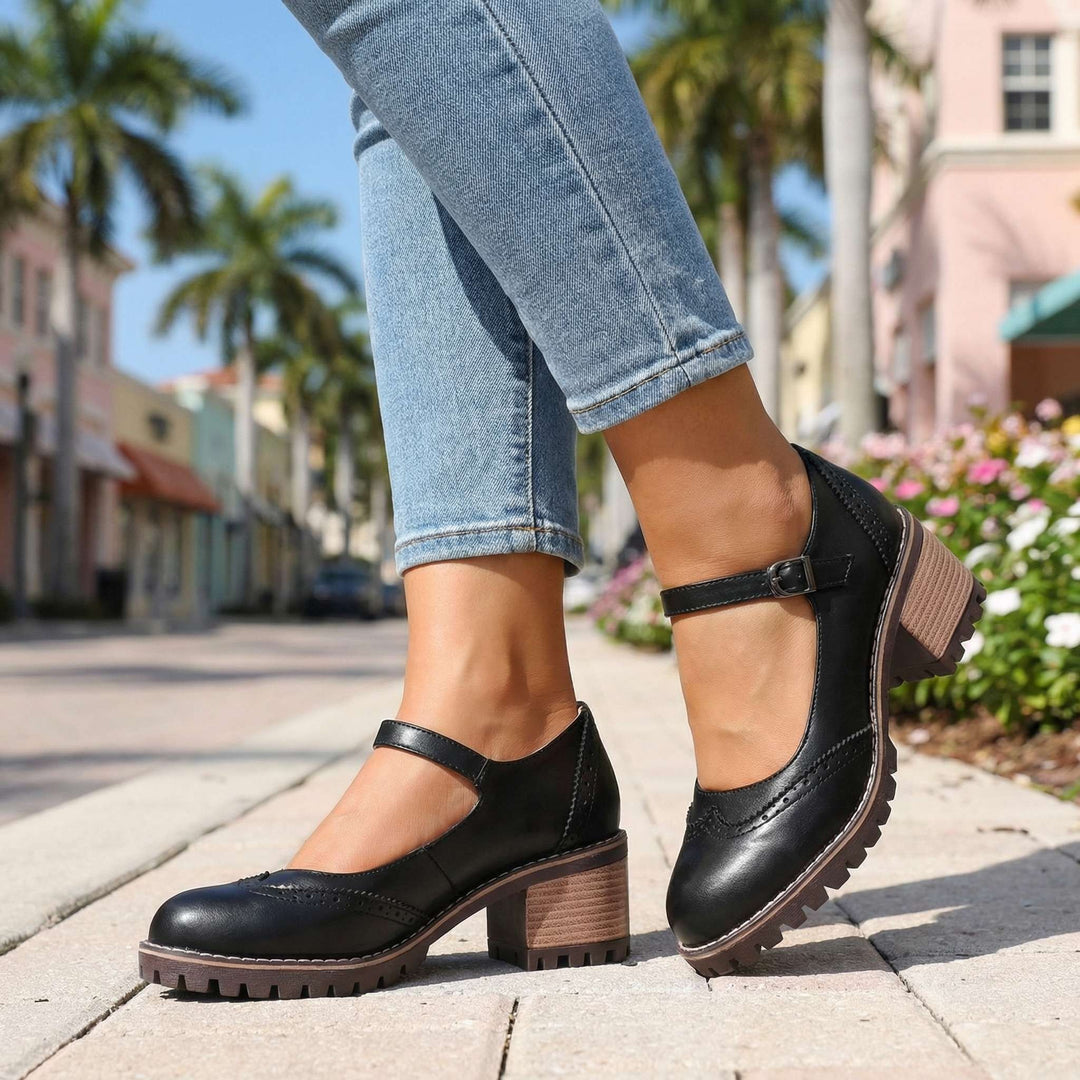 Black brogue Mary Jane shoes with ankle strap worn on cobbled pavement