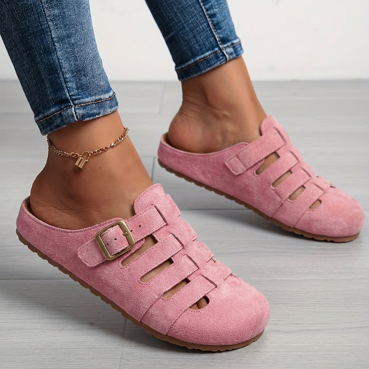 Pink suede cut-out mule sandals featuring gold buckle detail on foot