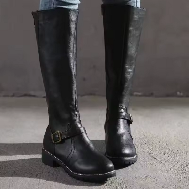 Front view of black leather knee-high boots with buckle and cleated sole