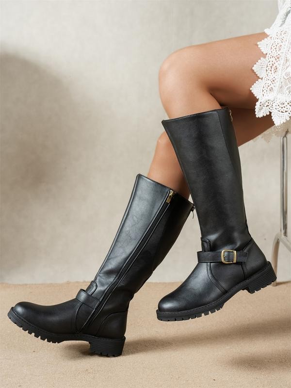Black knee-high riding boots with buckle strap and lugged low heel